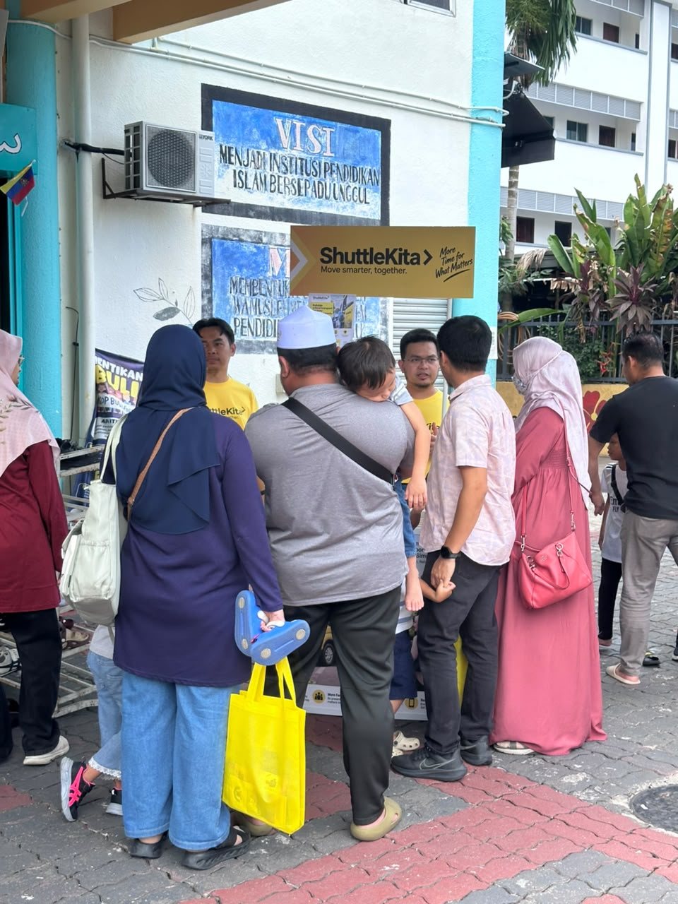 Parents and children gathered around the ShuttleKita booth at a school event